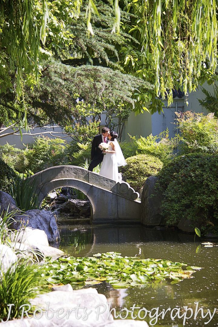 Bride and groom kissing on a bridge in the chinese gardens sydney - wedding photography sydney